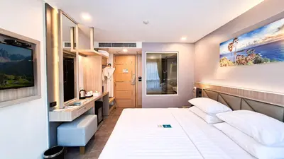 a hotel room with two beds and a sink at Clarian Hotel Beach Patong in Patong Beach