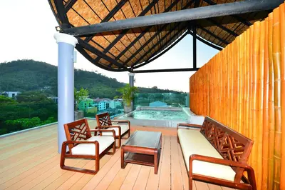 a deck with chairs and a table and a pool at Bukit Pool Villas - SHA Extra Plus in Patong Beach