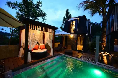 a swimming pool next to a house with a villa at Bukit Pool Villas - SHA Extra Plus in Patong Beach