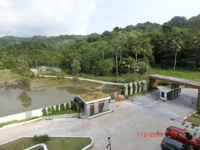 a building with a grass roof next to a river at The Naithorn Condo Unit 401 in Nai Thon Beach