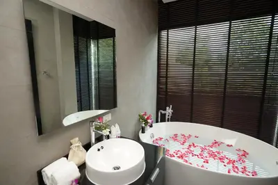 a bathroom with a tub and a sink and a mirror at Pumeria Resort Phuket - SHA Plus in Bang Tao Beach