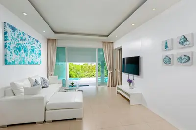 a living room with white furniture and a tv at Amala Grand Bleu Resort Hilltops - SHA in Kamala Beach