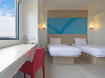 a room with two beds and a red chair at HOP INN Phuket in Phuket Town