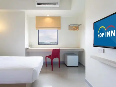 a room with a bed and a desk and a tv at HOP INN Phuket in Phuket Town