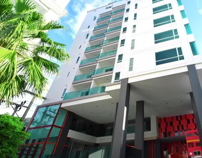 a tall white building with palm trees in front of it at Neon Patong in Patong Beach