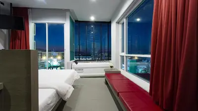 a bedroom with a bed and a large window with a tub at Neon Patong in Patong Beach