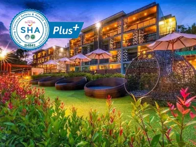 a hotel with umbrellas in front of a building at Maneetel Krabi Beachfront-SHA Plus in Ao Nang Beach