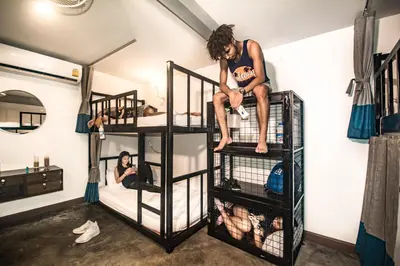 a man sitting on top of bunk beds in a room at Balcony Party Hostel - 18-40 in Ao Nang Beach