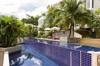 a swimming pool with palm trees next to a building at Kamala Hills Serviced Apartments in Kamala Beach