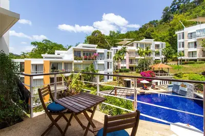 a balcony with a table and chairs and a swimming pool at Kamala Hills Serviced Apartments in Kamala Beach