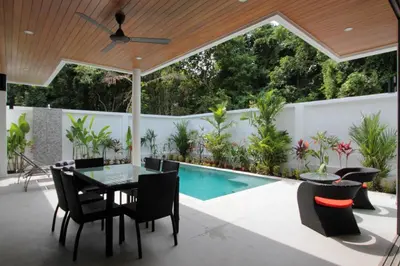 a patio with a table and chairs and a swimming pool at Ya Nui Beach Villas in Rawai Beach