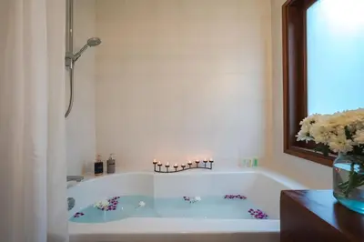 a bathroom with a tub with a vase of flowers at Vichuda Hills by RESAVA in Layan Beach