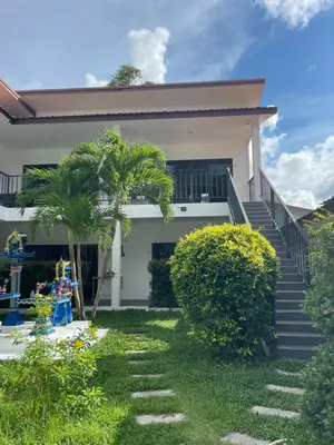 a white house with stairs and a palm tree at Lotus Bleu Resort & Restaurant in Rawai Beach
