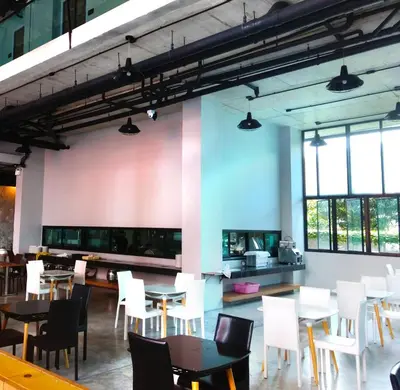 a dining room with white chairs and tables and windows at Phoenix Grand Patong in Patong Beach
