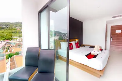 a bedroom with a bed and two chairs and a window at Phoenix Grand Patong in Patong Beach