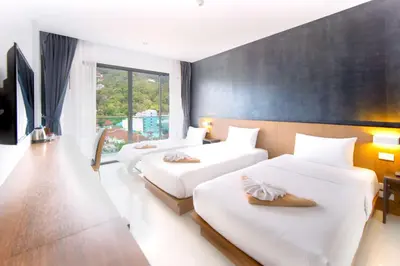 a hotel room with three beds with white sheets at Phoenix Grand Patong in Patong Beach
