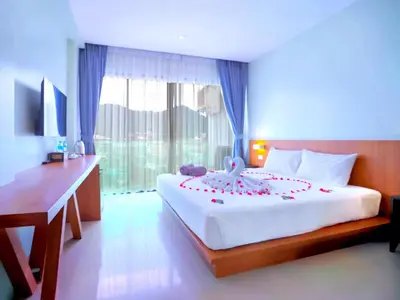 a bedroom with a large white bed with a desk at Phoenix Grand Patong in Patong Beach