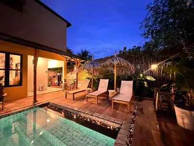 a house with a swimming pool and chairs next to a house at The Luna in Nai Yang Beach