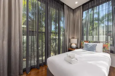 a bedroom with a large bed and large windows at VILLA PULAU 3 bedroom Baan Bua Estate in Nai Harn Beach
