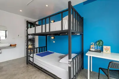 a bunk bed in a room with a blue wall at Hip Hostel - SHA Plus in Patong Beach