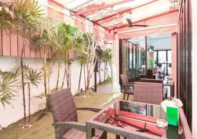 a patio with a table and chairs and palm trees at Buk Inn Hotel SHA Plus in Kamala Beach