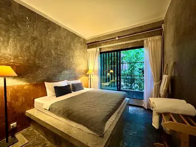 a bedroom with a bed and a large window at Phuchada Residence in Nai Yang Beach