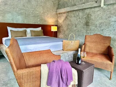 a bedroom with a bed and two chairs and a table at Phuchada Residence in Nai Yang Beach