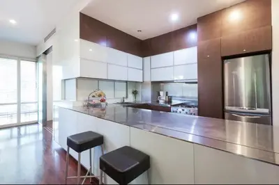 a kitchen with a large counter with two stools at Kata Gardens Apartments in Kata Beach