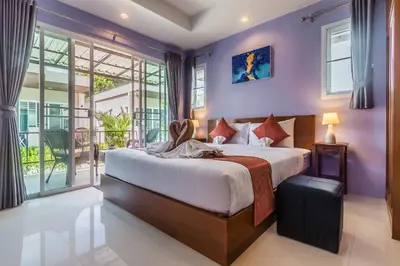a bedroom with a large bed with purple walls at Thuan Resort in Rawai Beach