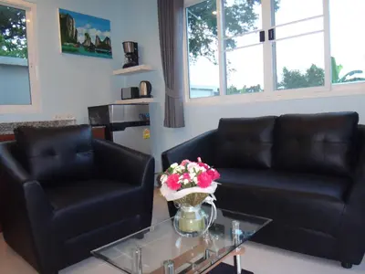 a living room with two leather chairs and a table with flowers at Thuan Resort in Rawai Beach