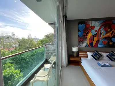 a room with a balcony with a bed and a window at Emerald Terrace Apartments by Lofty in Patong Beach
