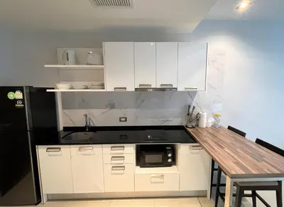 a kitchen with white cabinets and a wooden table at Emerald Terrace Apartments by Lofty in Patong Beach