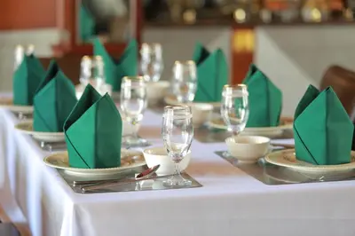 a long table with green napkins and wine glasses at Erawan Phangnga Hotel, Natai Beach in Khok Kloi