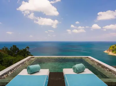 a swimming pool with two beds and the ocean at Villa Samira by Elite Havens in Kamala Beach