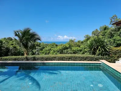 a swimming pool with the ocean in the background at Baan Phukhao in Klong Muang Beach
