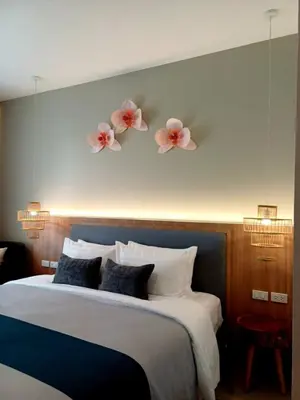 a bedroom with a bed with flowers on the wall at Mukrada House Boutique Hometel Krabi in Klong Muang Beach
