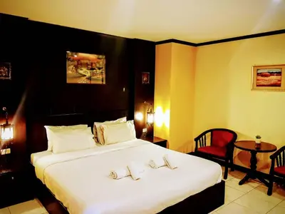 a bedroom with a large white bed with a red chair at Baantonkhaokata Hotel in Kata Beach