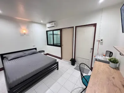a bedroom with a bed and a table in it at K.L.Apartment in Chalong