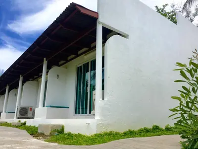 a white house with a green door at Sense of Yanui in Nai Harn Beach