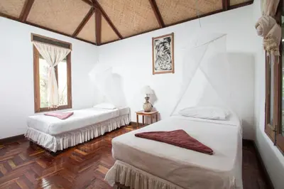 two beds in a room with white walls and wood floors at Tropical Garden Bungalow in Phi Phi Don