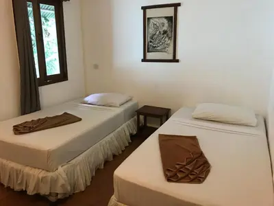 two beds sitting in a room with a mirror at Tropical Garden Bungalow in Phi Phi Don