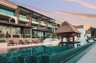 a large building with a swimming pool in front of it at Maikhao Palm Beach Resort - SHA Plus in Mai Khao Beach