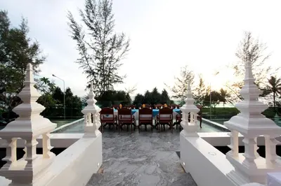 a group of people sitting around a table on a patio at Maikhao Palm Beach Resort - SHA Plus in Mai Khao Beach