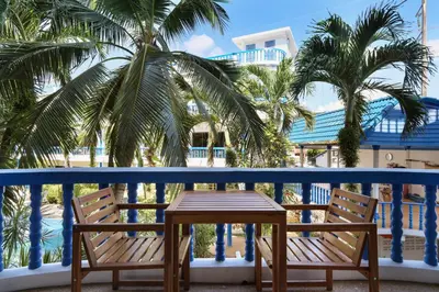 a table and chairs on a balcony with palm trees at The Club Residence Kamala Beach in Kamala Beach