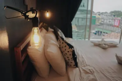 a lamp on a bed with pillows on it at Thira House in Karon Beach
