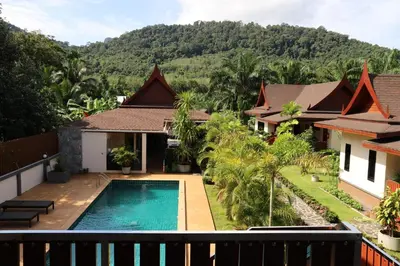 a villa with a swimming pool and mountains in the background at Chanapha Residence in Tab Kaek Beach