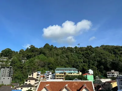 a group of buildings in front of a mountain at Baan Kingkeaw Thamdee Patong in Patong Beach