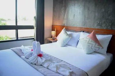 a bedroom with a bed with white sheets and pillows at Isayarada Apartment in Thalang
