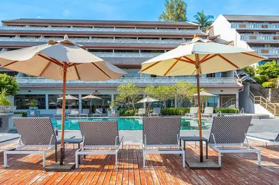 a group of chairs and umbrellas next to a pool at Orchidacea Resort - Kata Beach in Kata Beach