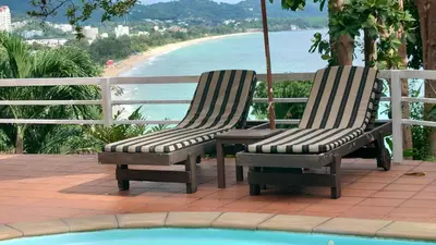 two chairs sitting next to a pool with a view of the beach at On The Hill Karon Resort in Karon Beach